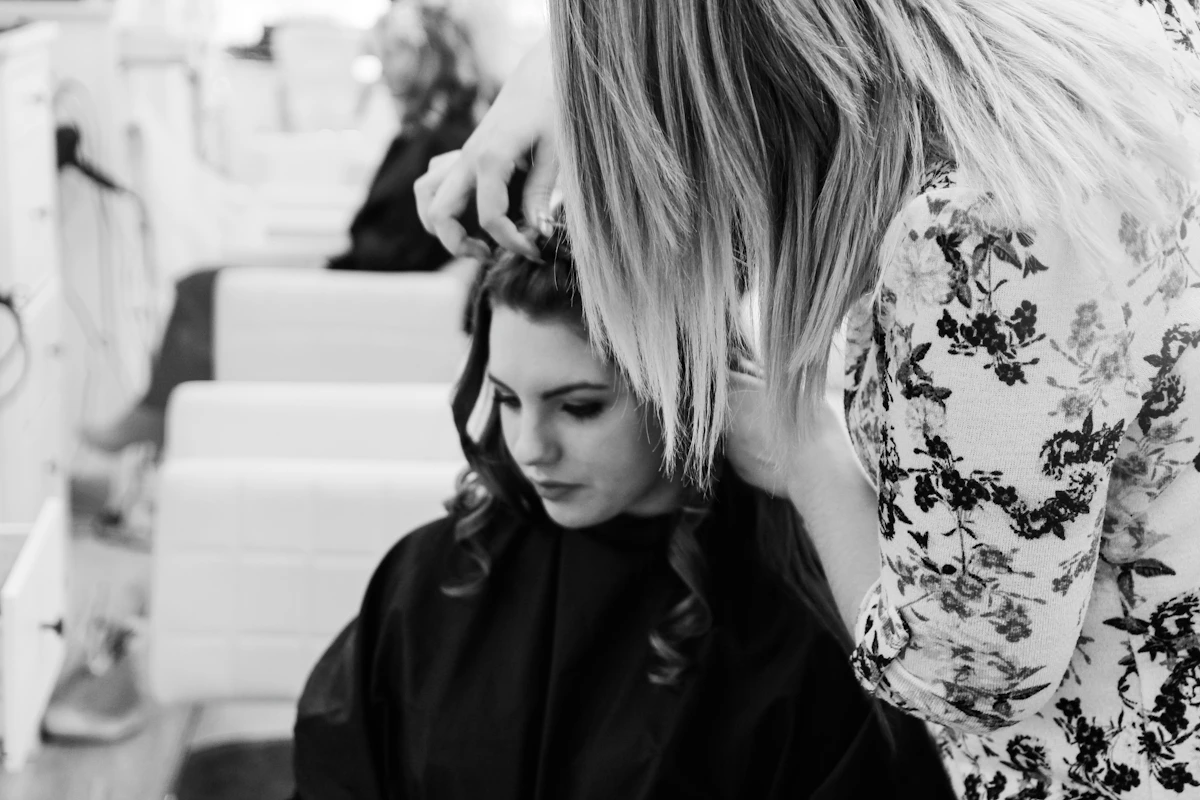 A stylist carefully curling a client’s hair
